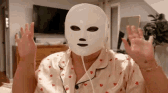 a woman is wearing a white mask on her face while sitting on a bed .
