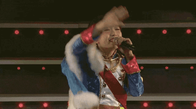 a woman singing into a microphone wearing a blue and gold outfit