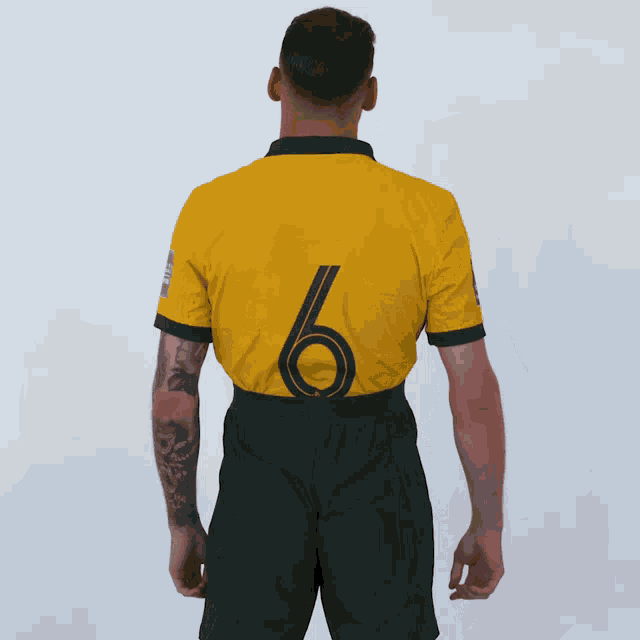 a man with a tattoo on his arm is wearing a yellow jersey with the number 6 on the back
