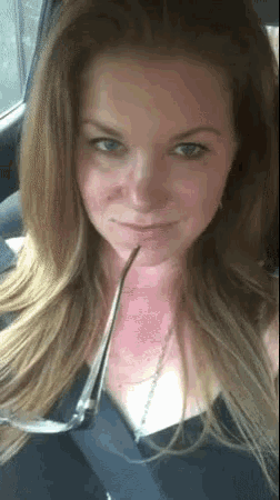a woman wearing glasses is sitting in a car and looking at the camera