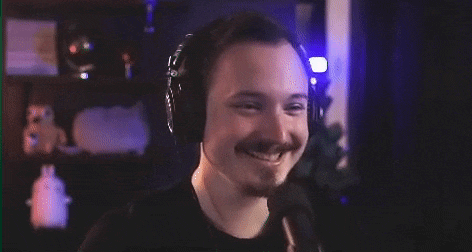 a man with a mustache is wearing headphones and smiling while talking into a microphone .