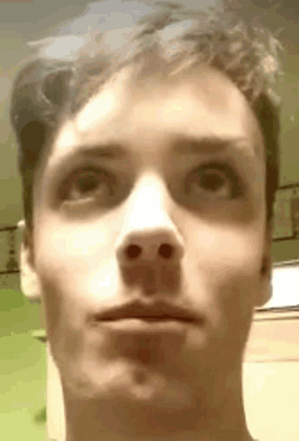 a close up of a young man 's face with his mouth open and his eyes looking up .