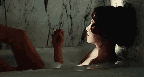 a woman is taking a bath in a bathtub with soap bubbles .