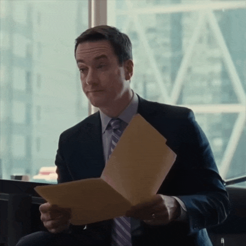 a man in a suit and tie is holding a folder of paper