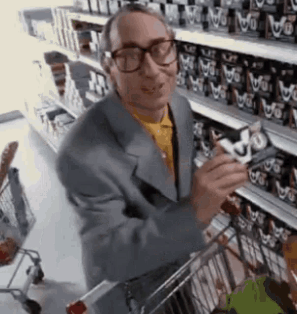 a man in a suit and glasses is shopping in a grocery store .