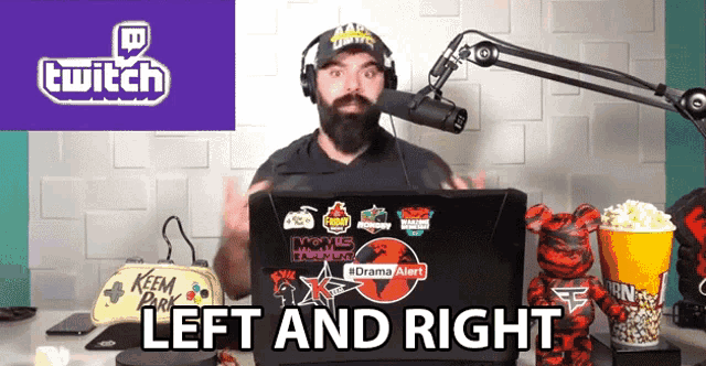 a man wearing headphones stands in front of a laptop with a sticker that says drama alert