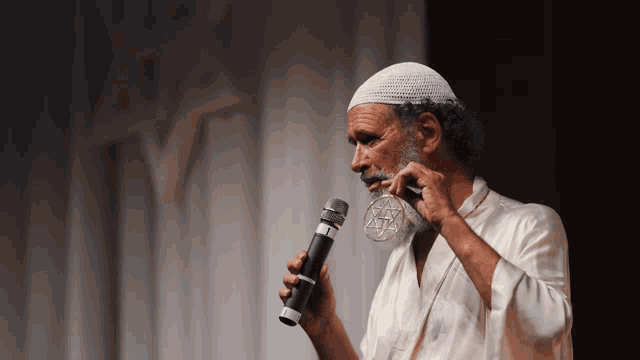 a man in a white hat is holding a microphone with a star of david on it