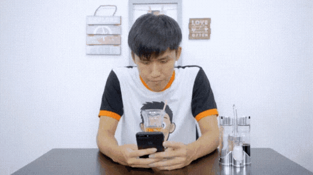 a man sitting at a table looking at a cell phone