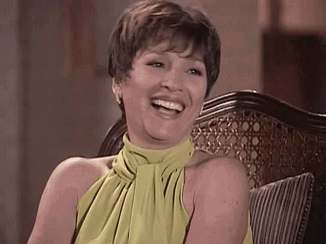 a woman in a green dress is sitting in a chair smiling .