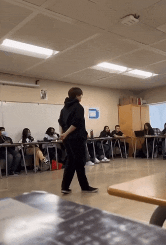 a man stands in front of a classroom full of students