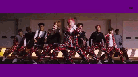 a group of young men are dancing in front of a building with a purple background