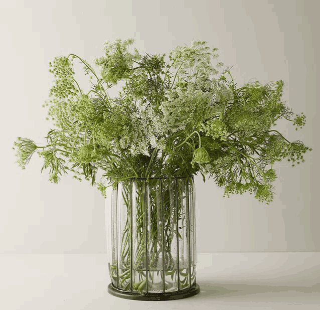 a glass vase filled with green and white flowers on a table