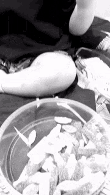 a black and white photo of a person eating a bowl of gummy worms .