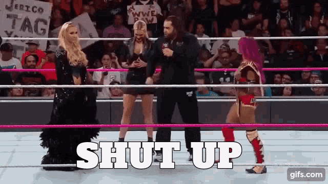 a female wrestler is standing in a ring with a referee and a sign that says shut up