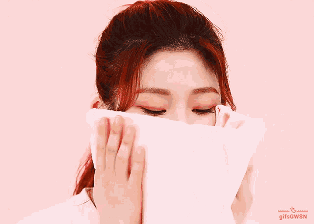 a woman covering her face with a pink towel with gifsgwsn written on the bottom