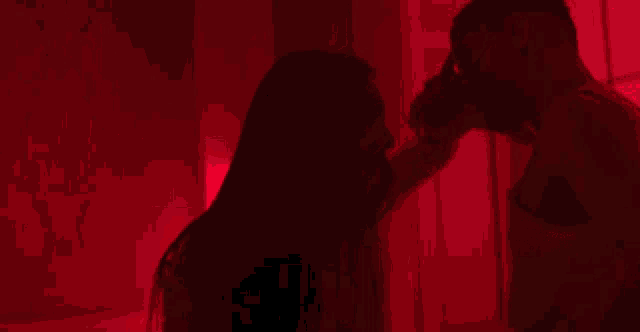 a man and a woman are dancing in front of a red light .