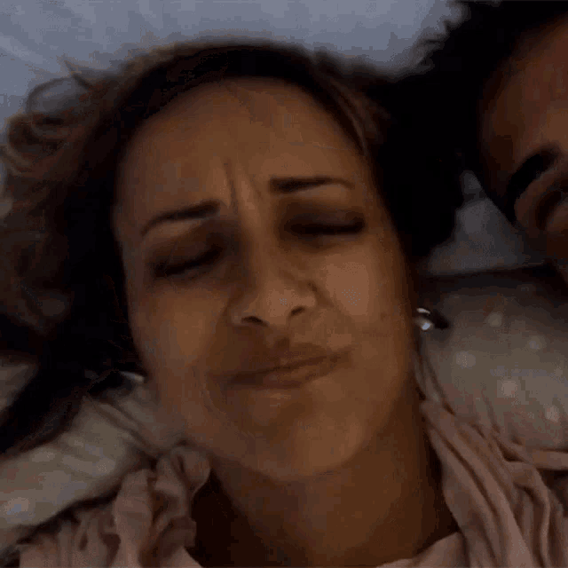 a woman laying next to a man with a sad look on her face