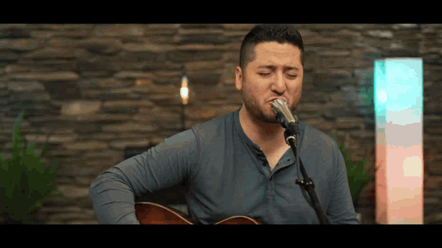 a man is singing into a microphone while holding a guitar