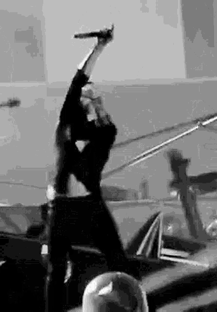 a black and white photo of a man holding a microphone in his hand .