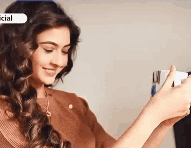 a woman is smiling while holding a cup of coffee in her hand .