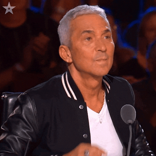 a man sitting in front of a microphone wearing a black jacket