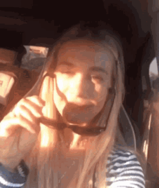a woman wearing sunglasses is taking a selfie in a car