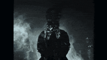 a black and white photo of a group of people standing in a foggy room .