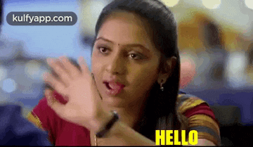 a woman is waving her hand and saying hello in a restaurant .