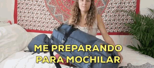 a woman is laying on a bed with a large blue bag that says me preparando para mochlar