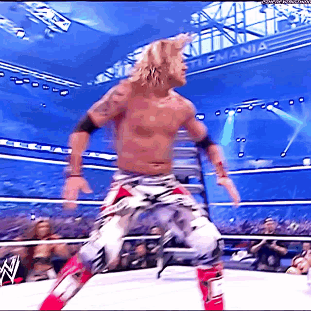 a man in a wrestling ring with a sign that says ' ultimate warrior ' on it