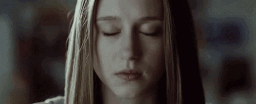 a woman with long blonde hair is looking down with her eyes closed .