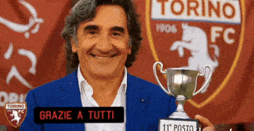 a man is holding a trophy in front of a torino fc logo