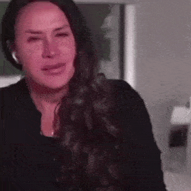 a woman is crying while wearing headphones and holding her hand to her chest .