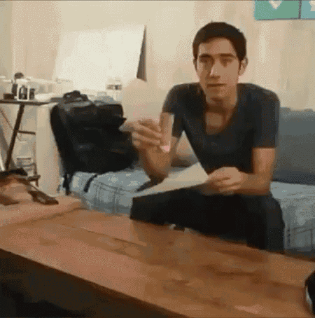 a young man is sitting on a couch holding a piece of paper .