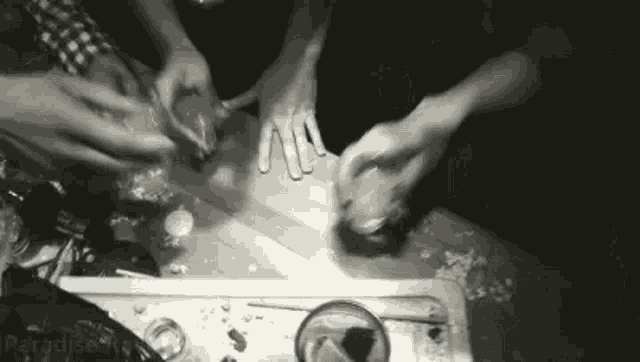 a black and white photo of a group of people playing with a bottle of alcohol .