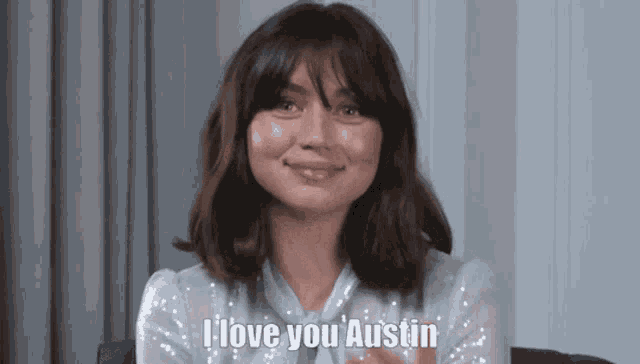 a woman is sitting in a chair and smiling while saying `` i love you austin '' .