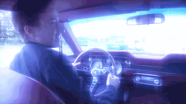 a man is sitting in a car with a steering wheel that says ' ford ' on it