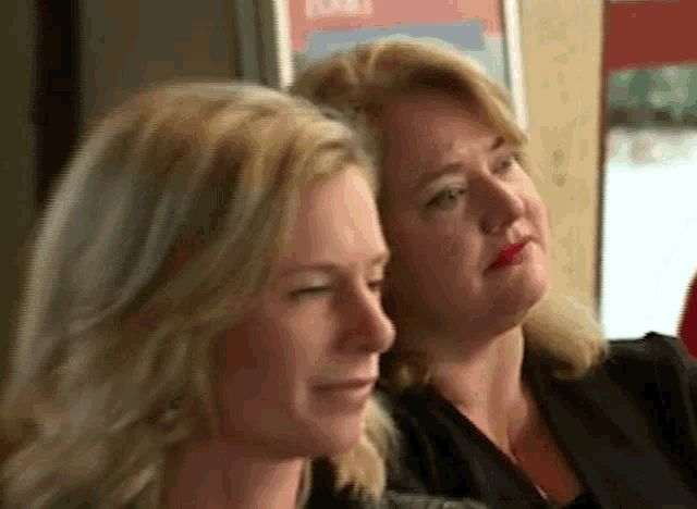 two women are sitting next to each other looking at something
