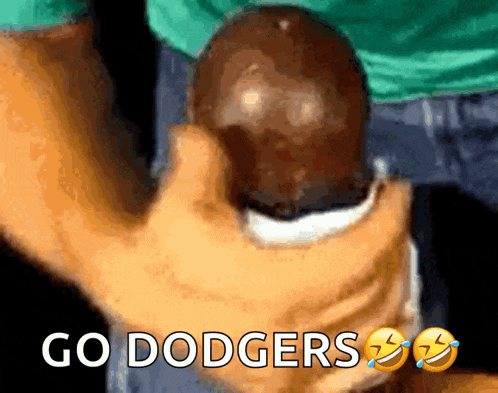 a person is holding a ball with the words go dodgers written on it
