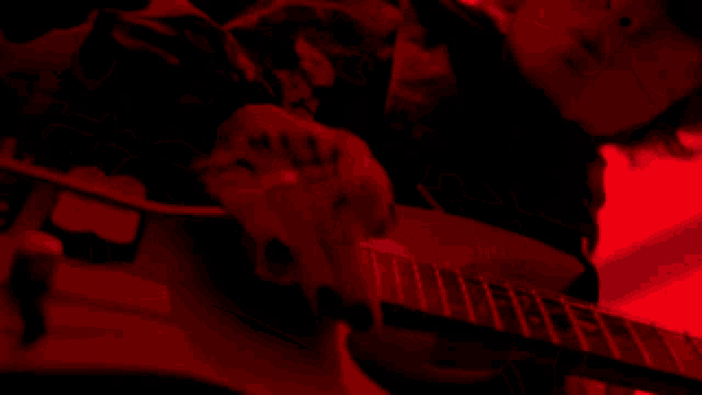 a person is playing a guitar with a red background