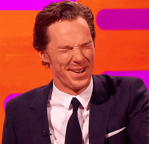 a man in a suit and tie is making a funny face while sitting on a stage .