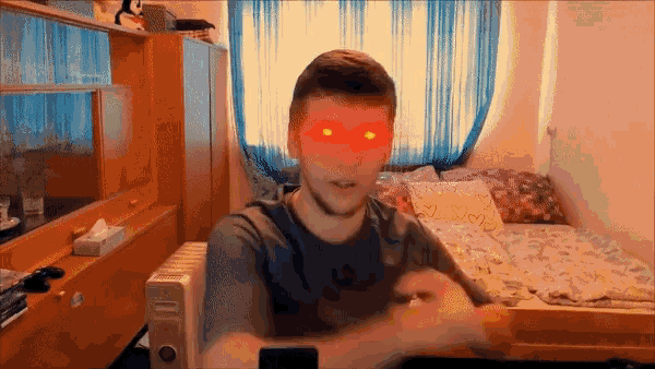 a man with red eyes is sitting in a bedroom