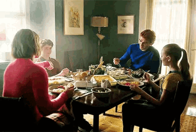 a family is sitting at a table eating a meal together .