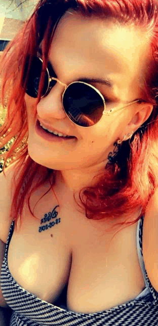 a woman with red hair wearing sunglasses and a tattoo on her chest that says ' a16 '