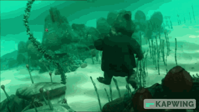 a cartoon character is swimming in the ocean with a kapwing logo behind him