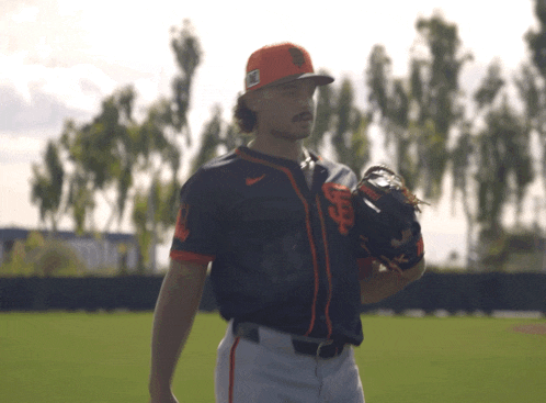 a man wearing a san francisco giants jersey stands on a field