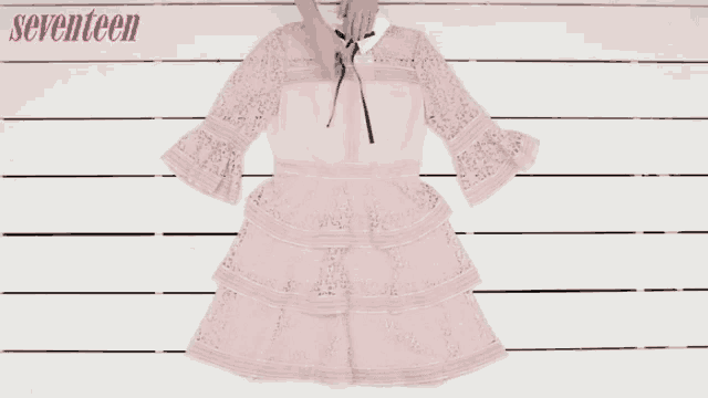 a woman is wearing a pink lace dress and white shoes with the words seventeen behind her