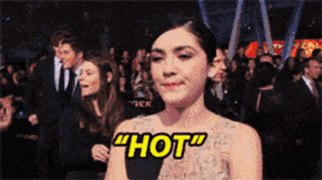 a woman is standing in front of a crowd and says hot