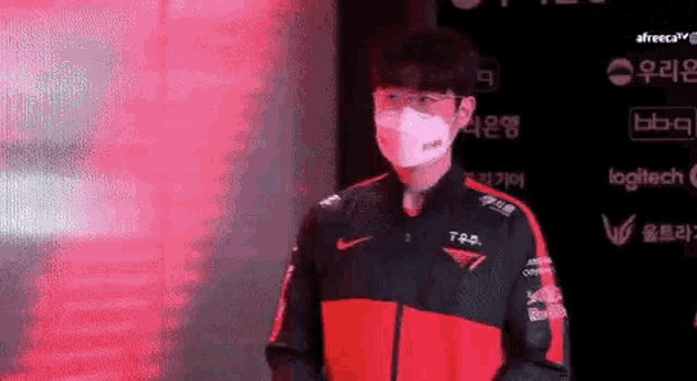 a man wearing a face mask and a red jacket is standing in front of a red background .