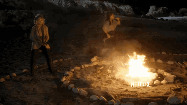 a netflix ad shows two people standing around a fire on the beach